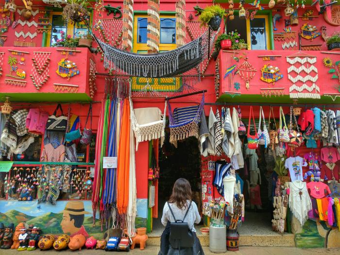 woman with backpack in front of red building decorated in souvenirs