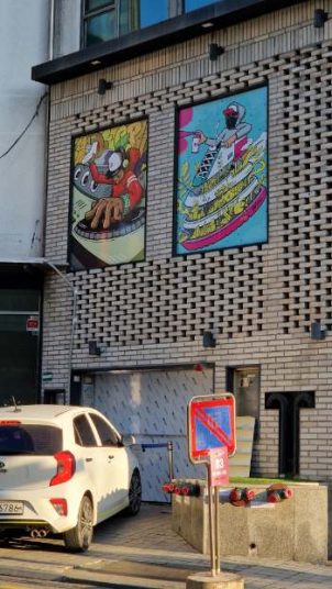 two murals depicting colourful food in comic-style on a grey building