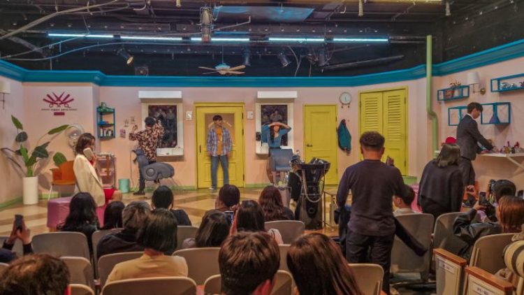 view of audience looking onto colourful stage with actors looking dramatically confused