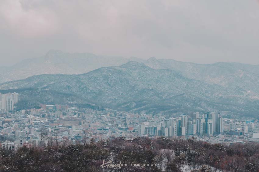 blue snowy mountains towering over skyscrapers in Seoul