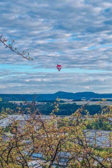 hot air balloon floating over a residential area and blue mountains in the background