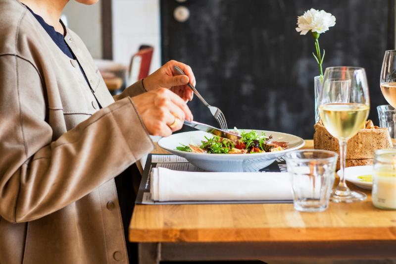 close up of woman#s hands cutting food on her plate at a restaurant