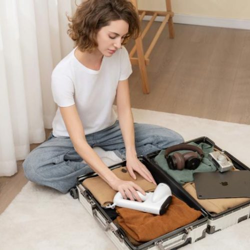woman sitting on floor packing a mall suitcase
